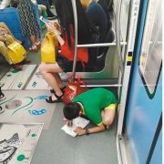 重庆一男孩趴在轻轨车门边写作业